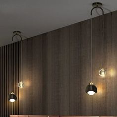 three lights hanging from the ceiling in a room with wood paneling and two couches