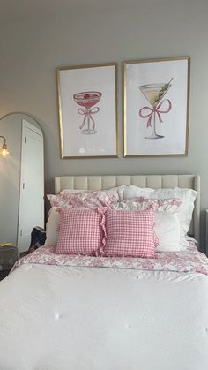 two framed pictures hang above a bed with pink and white linens on the headboard