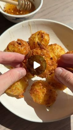 two hands reaching for some food on a white plate with chopsticks in it