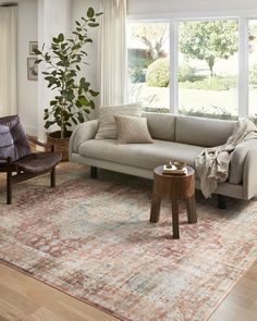 a living room filled with furniture and a large rug on top of a hard wood floor