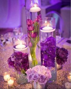 purple flowers and candles in glass vases on a table