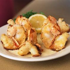 a white plate topped with shrimp and lemon wedges