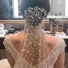 the back of a woman's head wearing a wedding veil with flowers on it