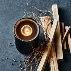 a candle sitting on top of a wooden block next to some sticks and wood shavings