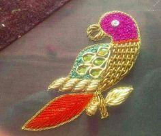 a colorful bird brooch sitting on top of a piece of cloth