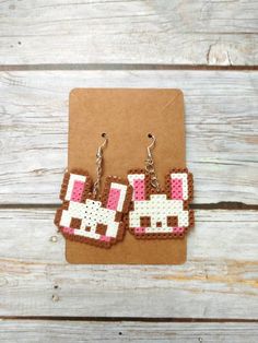 the pixelated dog earrings are made out of brown and white beads with pink dots on them