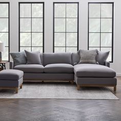 a living room filled with lots of furniture and large windows in the wall behind it