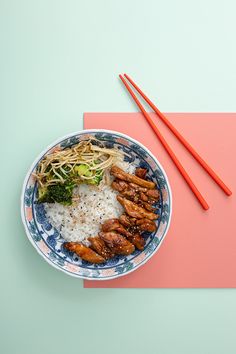 a blue and white plate topped with rice and meat next to chopsticks