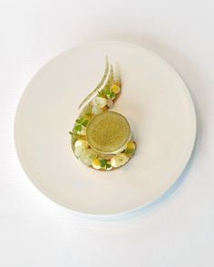 a white plate topped with a dessert covered in green and yellow topping on top of it