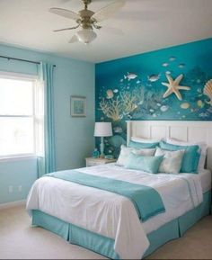 a bedroom decorated in blue and white with an ocean theme on the wall above the bed