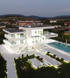 an aerial view of a modern house with pool in the foreground and surrounding landscaping