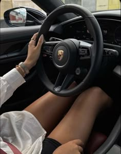 a woman sitting in the driver's seat of a car with her hands on the steering wheel