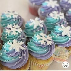 cupcakes with blue frosting and white snowflakes on them are displayed