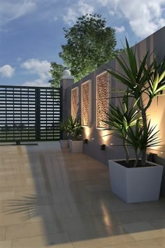 an outdoor patio with potted plants and lights on the wall, along with a fenced in area