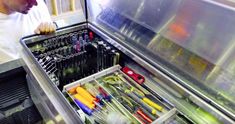 a man is looking into an open drawer with many tools in it and he is trying to find the right one