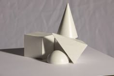 a white sculpture sitting on top of a table next to two balls and a cone