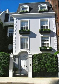 a large white house with many windows and plants on the top of it's balconies