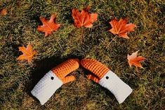 an orange and white knitted glove laying on top of green grass next to leaves