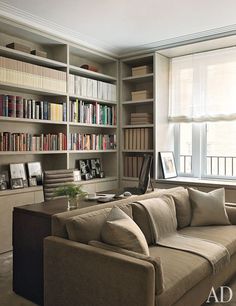 a living room filled with furniture and bookshelves next to a window covered in lots of books