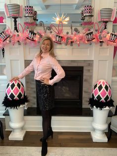 a woman standing in front of a fireplace with pink and black decorations on the mantle