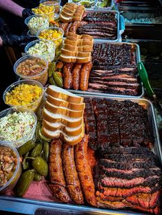 many different types of meats and other foods on display in trays at an outdoor market