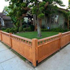 a wooden planter in front of a house with trees and bushes on the side