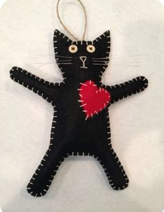 a black cat ornament with a red heart on it's chest and eyes