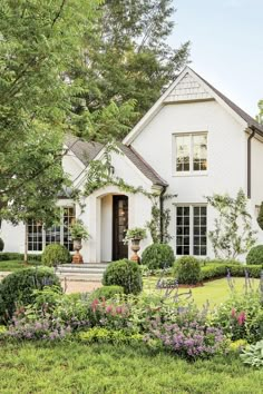 a white house surrounded by flowers and trees