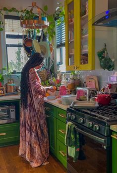 a woman is standing in the kitchen with pots and pans hanging above her head