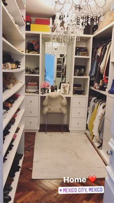 a walk in closet with chandelier and shelves full of shoes on the floor