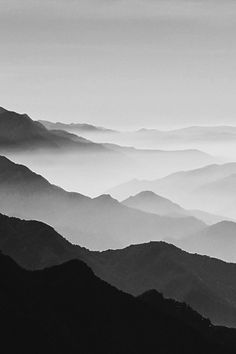 black and white photograph of mountains with fog