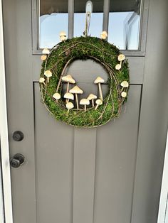 a wreath with mushrooms is hanging on the front door