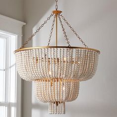 a chandelier with beads hanging from it's ceiling in front of a window