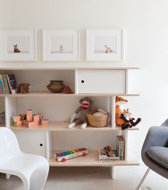 a living room filled with furniture and pictures on the wall next to a white chair