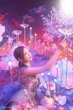 a woman is standing in front of some fake flowers and plants with lights on them