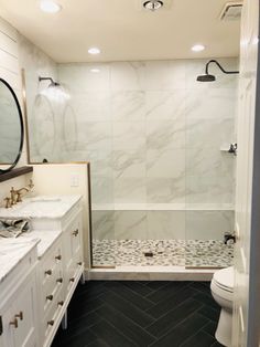 a bathroom with white cabinets and marble counter tops, along with a walk in shower