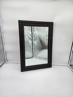 a black framed mirror sitting on top of a white floor