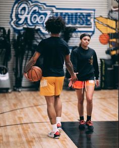 a man and woman walking on a basketball court with the ball in their other hand