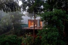 a house in the middle of some trees with a deck on it's side