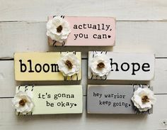 four wooden signs with flowers and words on them