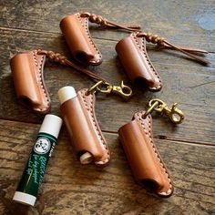 four leather keychains with two lighters and one tube on the ground next to them