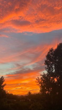 an orange and pink sky at sunset over trees