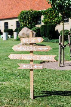 a wooden sign in the grass pointing to different places