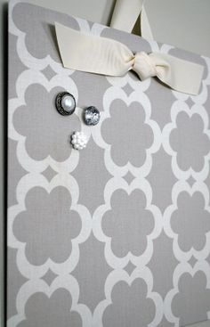 a gray and white wall hanging with buttons on it