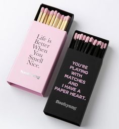 two matches are in a pink box and one is black with white writing on it