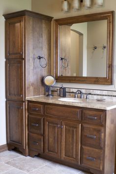 a bathroom with wooden cabinets and a large mirror on the wall over the sink area