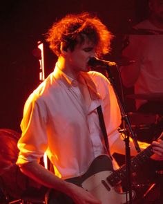 a young man playing an electric guitar on stage