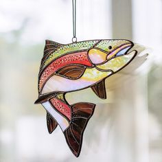 a stained glass fish ornament hanging from a window