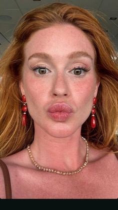 a woman with freckled hair and earrings making a funny face at the camera