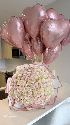 a bouquet of pink roses and heart shaped balloons in a vase on a kitchen counter